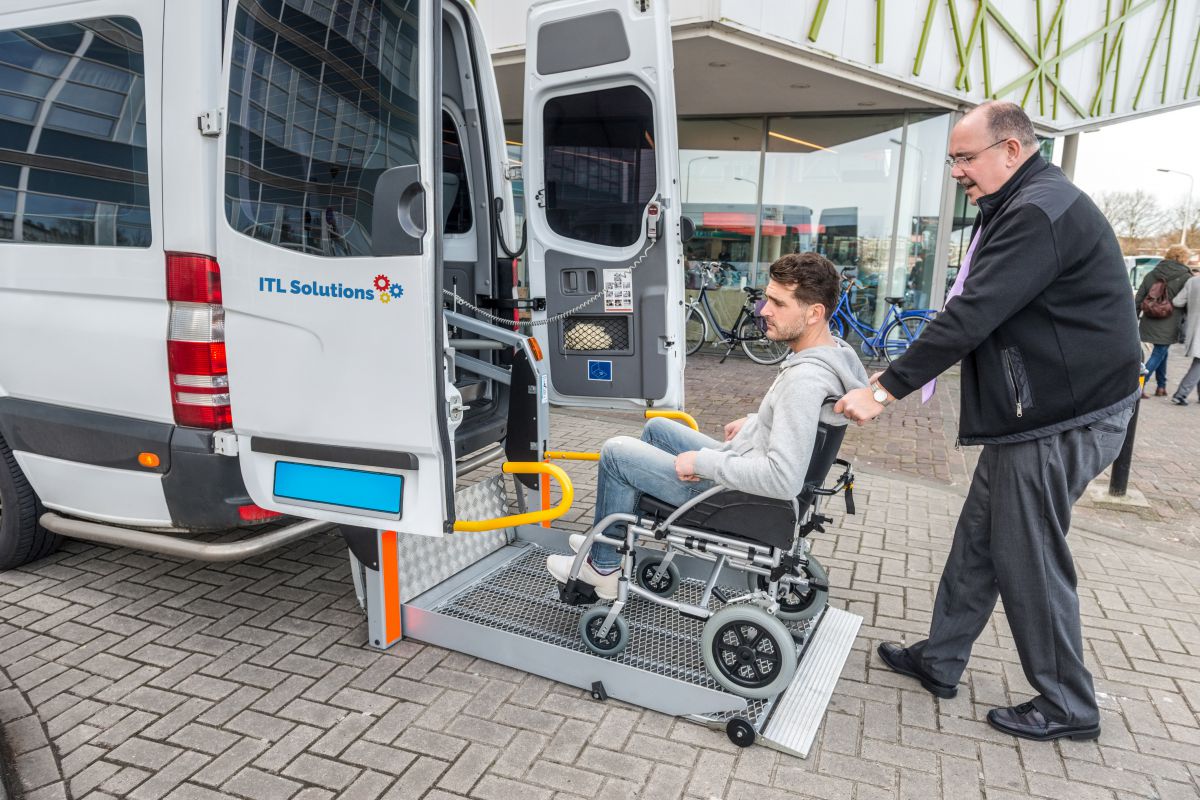 Man in wheelchair pointing at handicap sticker on bus